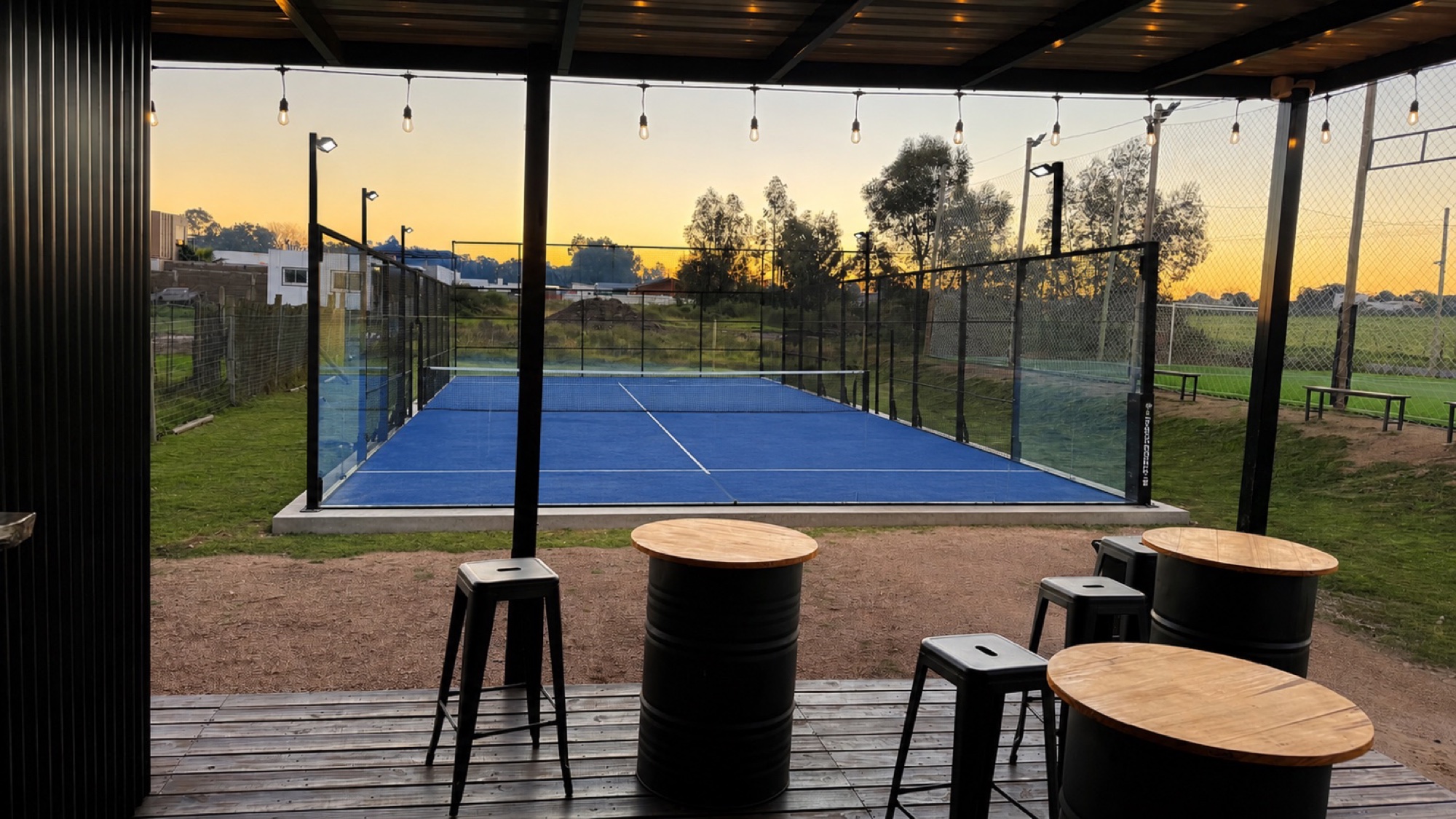 Cancha de pádel de Estación 97 al atardecer, vista desde la cantina